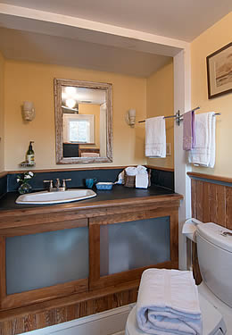 A cabinet sink in a fresh bathroom with a white toilet, beige walls and a wood panel surround.