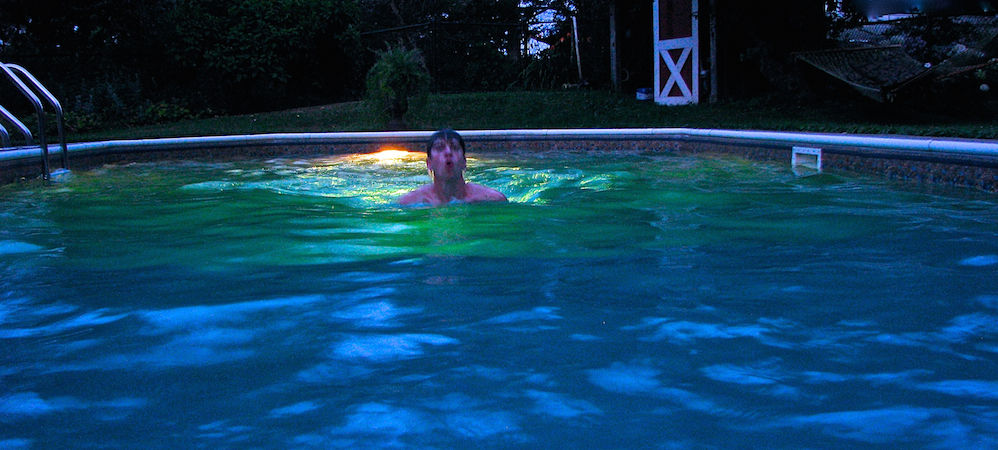 man swimming in a pool at night